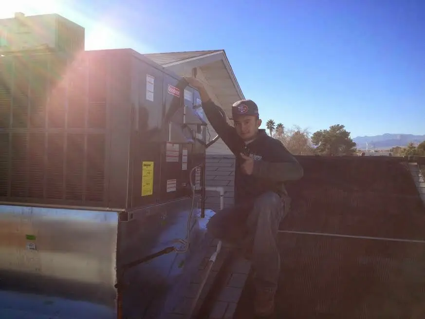 HVAC technician performing Air Duct Cleaning on a rooftop unit in West Slope